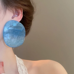 Detailed close-up of blue resin wavy earrings worn by a model for a stylish look