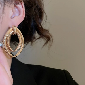 Close-up of golden multi-layer nesting geometric hoop earrings worn on a model's ear