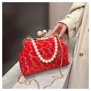 Close-up of red velvet shell bag with gold pattern, pearl handle and chain strap