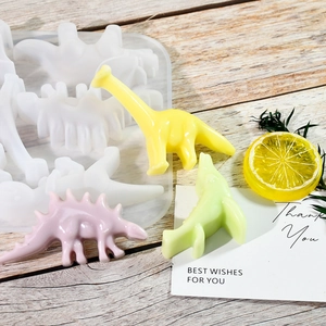 Makro-Detail von Dinosaurier-Silikonformen mit bunten Harzanhängern auf Holzoberfläche