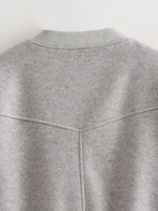 Détail du col d'une veste de baseball gris clair avec bord-côte et couture dorsale en V