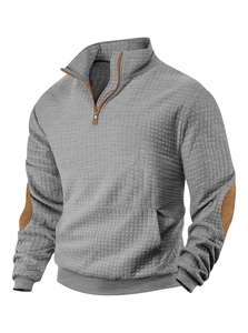 Detailed view of grey waffle textured sweatshirt featuring brown suede elbow patches