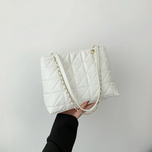 Quilted white tote bag with gold chain strap in a minimalist fashion style
