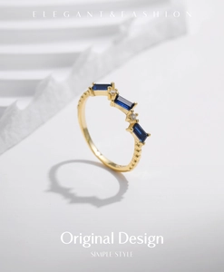 Detail of gold ring featuring three emerald-cut blue stones and textured band design