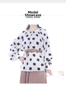 Detail of white polka dot blouse styled with a brown belt and pleated skirt
