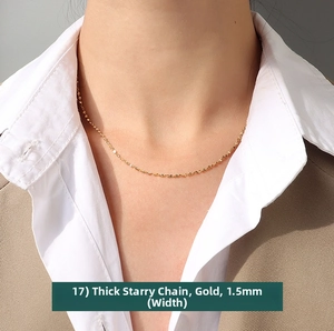 Close-up of 1.5mm gold plated star chain necklace worn with a white shirt and blazer