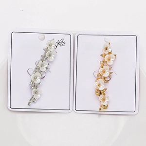 Close-up of gold and silver plum blossom branch brooches on white fashion jewelry cards