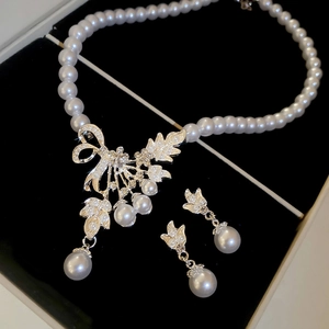 Detailed set of pearl necklace and bow earrings with rhinestones in a velvet box