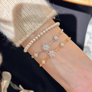 Detailed shot of layered pearl and floral bracelets with sparkling rhinestones in gold and silver
