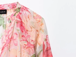 Dettaglio del colletto della camicetta floreale rosa in tessuto chiffon traslucido