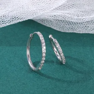 Polished silver stainless steel hoop earrings with sparkling white crystals on green velvet
