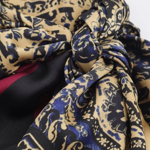 Macro shot of paisley print silk dress fabric with gold and blue leopard pattern detail