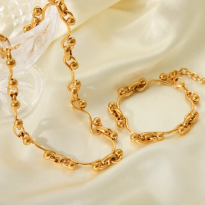 Close-up of golden horseshoe link necklace and bracelet set on soft satin fabric