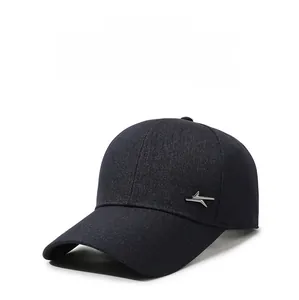 Close-up of deep blue denim baseball cap with silver metal geometric logo and curved brim