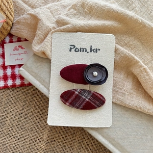 Detail of red fabric bow hair clips with pearls and plaid pattern on display card