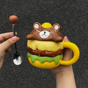 Detail of cute burger-shaped ceramic mug with brown bear lid and matching metal spoon
