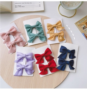 Detailed set of twelve colorful bow hair clips in various satin fabrics on card