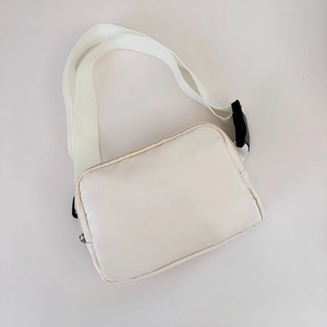 Detail view of cream nylon waist bag with adjustable woven strap and plastic buckle