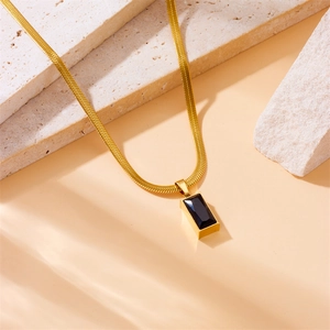 Minimalist gold snake chain necklace with black rectangular pendant on stone