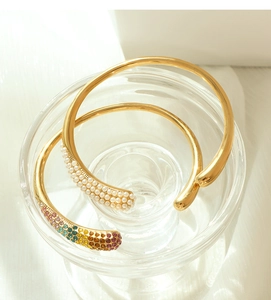 Détail de bracelets joncs plaqués or 18k avec perles et cristaux arc-en-ciel