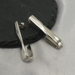 Polished silver stainless steel U-shaped stud earrings on minimalist black slate