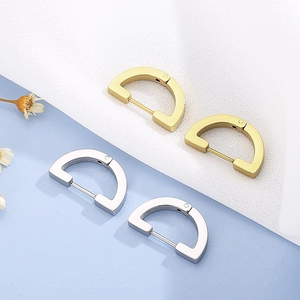 Detail of minimalist gold and silver D-shaped hoop earrings on a textured background