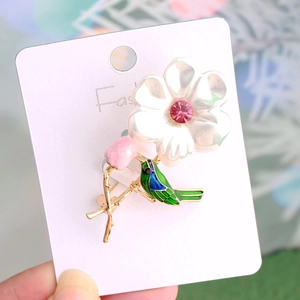 Macro shot of bird and flower brooch with colorful enamel details and sparkling crystals