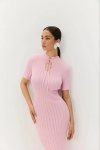 Dettaglio dell'abito in maglia rosa con scollo a goccia e trama a costine verticali