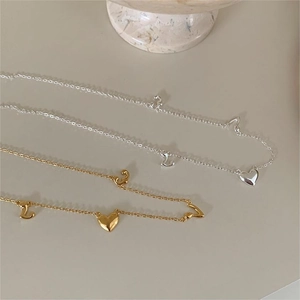 Detail of silver and gold heart and LOVE pendant necklaces on minimalist background