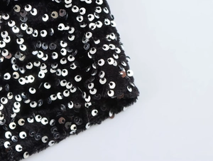 Macro shot of silver sequins on black plush fabric detail for asymmetrical dress