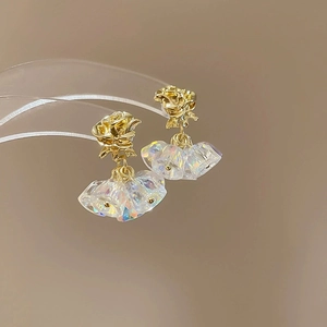 Macro detail of golden rose earrings with clear iridescent floral crystal pendants