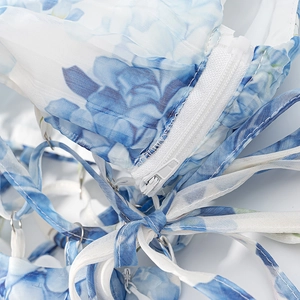 Detail of floral dress showing white zipper closure and crisscross shoulder straps