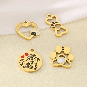 Detail of 18k gold-plated heart, bone and paw charms on beige textured background
