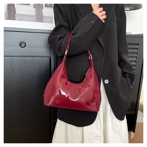 Detail of glossy deep red patent leather shoulder bag with metallic buckle strap