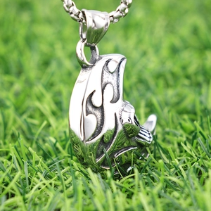 Gothic punk moon skull necklace with silver totem engraving on green grass background