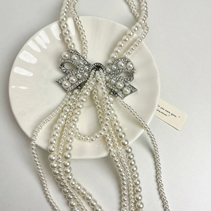 Elegant multi-layer pearl bridal necklace with crystal bow pendant on ceramic dish
