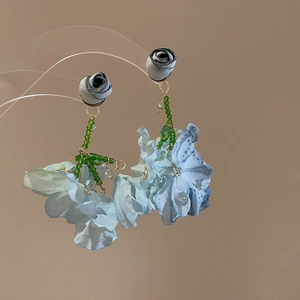 Close-up of bohemian blue fabric flower earrings with grey rose buds and green beads