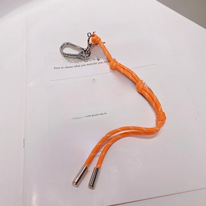 Détail d'un cordon tressé orange à pois blancs avec fermoir mousqueton en métal argent