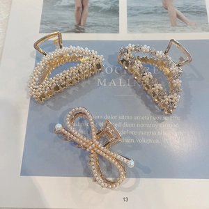 Flat lay of gold hair claws with pearls and rhinestones on a magazine background