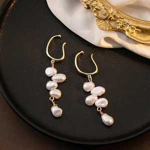 Macro detail of French vintage earrings with irregular pearls on a gold tassel drop