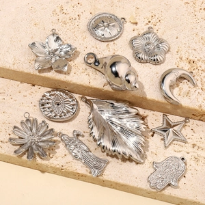 Various silver stainless steel DIY pendants including shells and stars on beige stone
