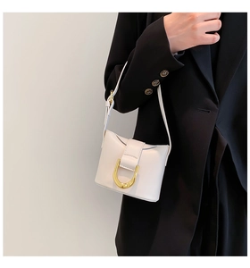 Close-up of white leather mini square bag with golden U-shaped buckle on black blazer