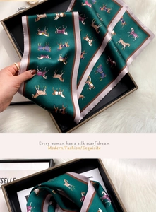 Macro view of green silk scarf with horse print neatly placed in a premium black gift box