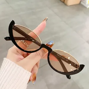 Occhiali da sole vintage cat eye con montatura nero oro e lenti marroni scuri in mano
