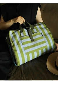 Detail of green and light blue striped fabric travel storage bag with webbed handles
