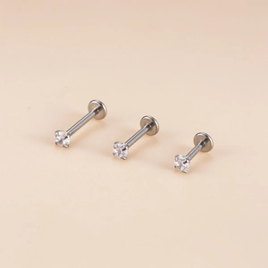 Macro shot of stainless steel labret studs with various zircon sizes on beige background