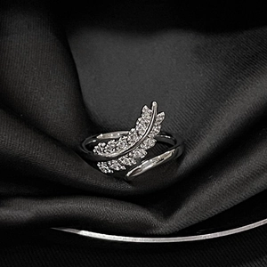 Macro shot of silver feather ring with micro-pave diamonds on black silk background