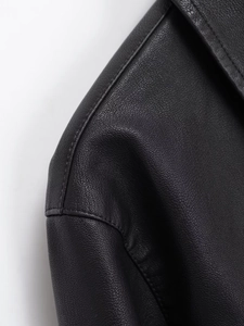 Détail macro d'une veste en similicuir noir montrant le grain fin et les coutures de col