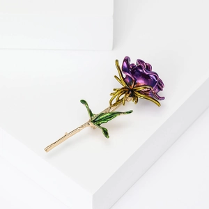 Elegant purple rose brooch with golden metal leaves on a white geometric background