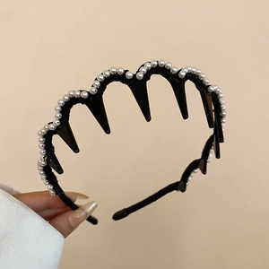 Detail of black wavy headband featuring white pearls and hair-securing teeth combs